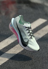 Light green running shoe with textured upper, black swoosh logo, and pink-accents on the sole, featuring a sleek, aerodynamic design.