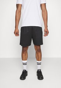 Black mesh athletic shorts, featuring an elastic waistband, paired with black shoes and white socks with black stripes.
