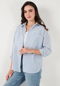 Blau-weiß gestreiftes Hemd mit Knopfdesign, zwei Brusttaschen und aufgerollten Ärmeln, aus leichtem Stoff gefertigt.