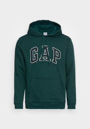 Felpa in cotone verde scuro con tasca a canguro frontale e cappuccio con cordoncino. Presenta una grande scritta "GAP" in bianco a contrasto.