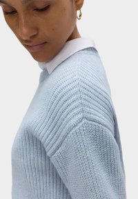 Jasnoniebieski sweter z dzianiny z teksturowanym ściągaczem, okrągłym dekoltem i kontrastującym białym kołnierzykiem; miękki materiał z luźnym krojem.