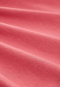Tissu en coton de couleur corail atténuée, avec une texture lisse et des drapés subtils, sans motifs ni accents visibles.