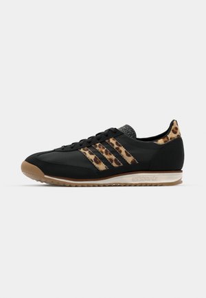 Black athletic shoe featuring a leopard print upper, three signature stripes, and a gum rubber sole. Textured heel and lace-up front.
