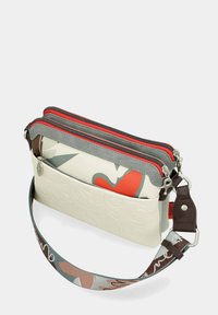 Borsa a tre scomparti con fondo bianco testurizzato, dettagli grigi e rossi con zip e una tracolla decorata con cuori e swirl.
