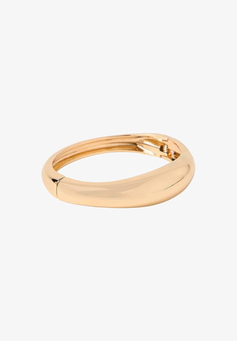 Bracciale in oro levigato e lucido con un design arrotondato e leggermente torcido, dotato di una chiusura a cerniera visibile su uno sfondo bianco.