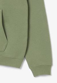 Felpa verde chiaro in morbido cotone, con tasca a marsupio frontale, polsini e orlo a costine. Caratterizzata da un design pulito e minimalista.