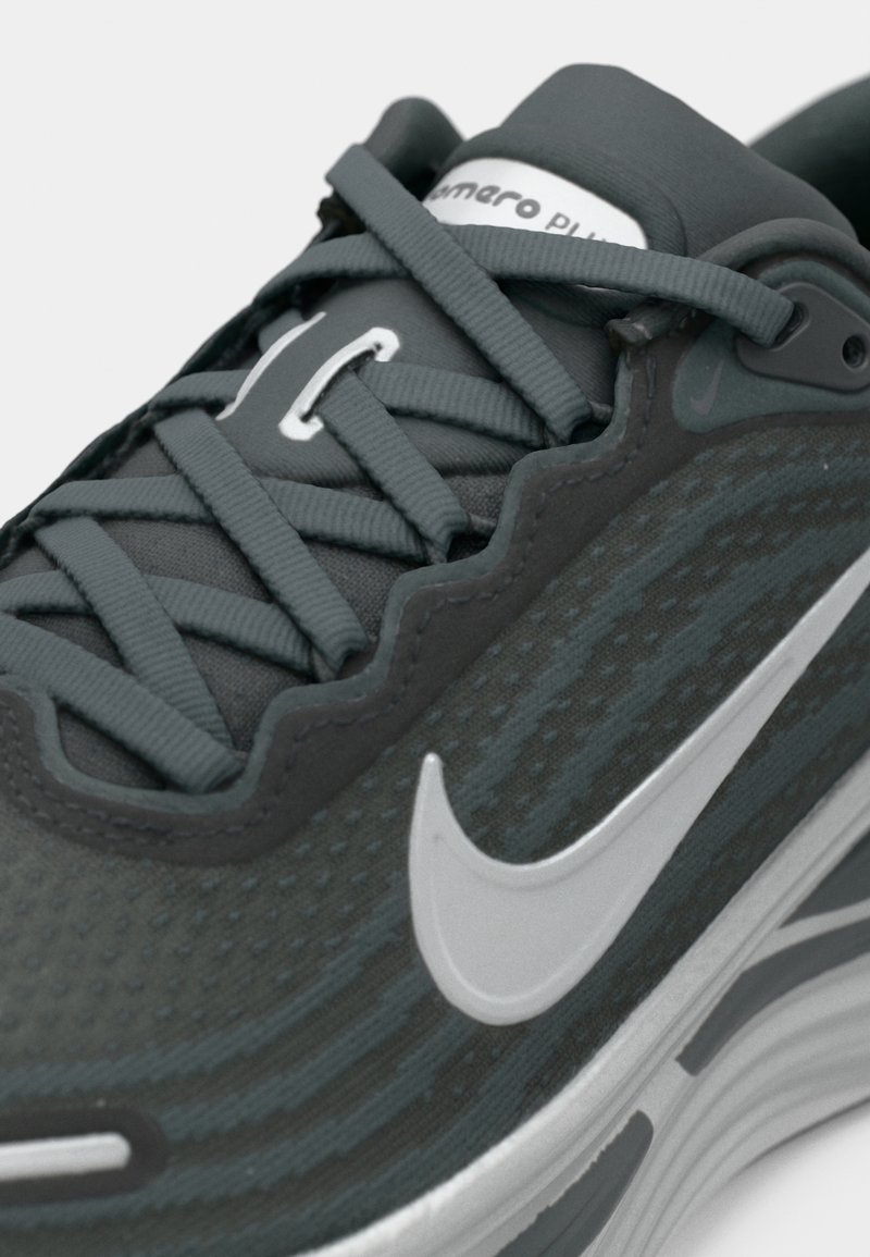 Nahaufnahme eines dunkelgrauen Nike Laufschuhs mit hellgrauem Swoosh-Logo und dicker, gepolsterter Sohle.