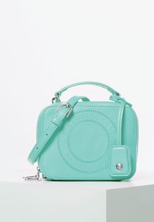 Mała miętowo-zielona prostokątna torba na ramię z górnym uchwytem, regulowanym paskiem, wypukłym okrągłym logo oraz przyczepioną metką z srebrnym guzikiem.