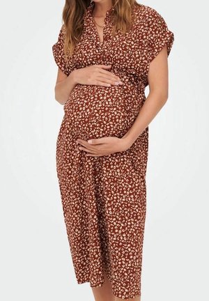 Graviditetkjole i brun med hvidt blomsterprint, korte ærmer og løs pasform, med omslagsdesign og knælængde.