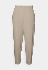 Beige Jogginghosen mit elastischen Bündchen und Kordelzug am Bund. Verfügen über seitliche Falten und ein kleines weißes Logo an der linken Hüfte.