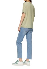 Lichtgroene katoenen t-shirt met korte mouwen, gecombineerd met lichtblauwe rechte jeans en witte sneakers met muntgroene accenten.