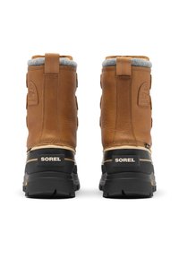 Ruskeat nahkasaappaat harmaalla fleecellä vuoratulla sisäosalla, joissa on musta kumipohja ja merkintä takana. Vankka rakenne ja vetonauhat.