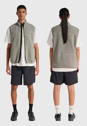 To modeller iført grå fleeceveste over hvide T-shirts og sorte shorts, vist forfra og bagfra mod en ensfarvet baggrund.