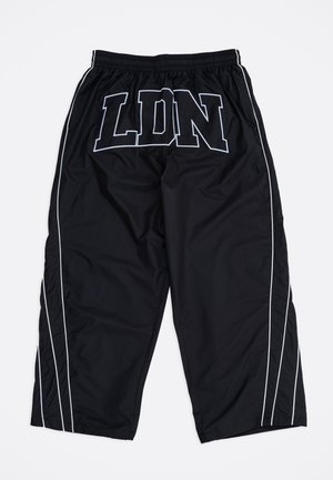 Zwarte sportbroek met witte zijstrepen en grote "LDN" letters met witte omtrek op de voorste tailleband, elastische taille, losse pasvorm.