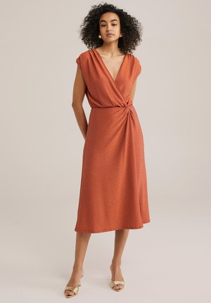 Kupferfarbenes Kleid mit Wickeldesign, kurzen Ärmeln und einer Knoten-Detail an der Taille. Der glatte, strukturierte Stoff fällt bis zur Mitte der Waden.