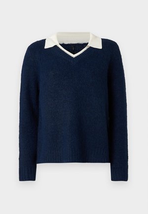 Tumši zilā džemperis ar teksturētu apdari, V-veida kakla izgriezumu un kontrastējošu baltu apkaklīti. Iezīmē garas piedurknes un brīvu piegriezumu.