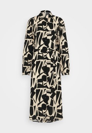 Juoda ir kreminė raštuota suknelė su apykakle, ilgomis rankovėmis ir mygtukų užsegimu priekyje. Suknelės juosmenyje yra diržas, o jos dizainas yra abstraktus.