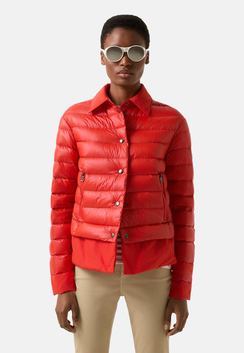 Rote Steppjacke mit vorderer Knopfverschluß, horizontalem Steppmuster und Reißverschlusstaschen an den Seiten. Der Stoff ist glänzend und glatt.