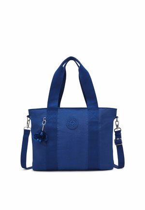 Blaue Stofftasche mit doppelten Griffen, abnehmbarem Schulterriemen und einem kleinen Plüsch-Schlüsselanhänger an der vorderen linken Seite.