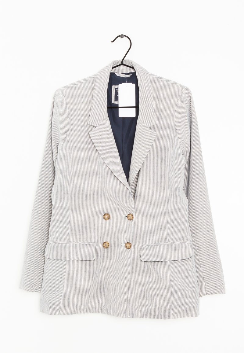 Jasnoszary dwurzędowy żakiet w paski z czterema brązowymi guzikami i kieszeniami z klapami wiszący na czarnym wieszaku.