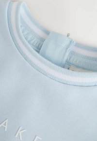 Hellblaues Sweatshirt mit geripptem Kragen in Weiß und Blau. Verfügt über eine strukturierte Oberfläche und das "BAKER"-Logo in Weiß. Etikett ist auf der Rückseite sichtbar.