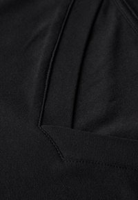 Czarna tkanina o gładkiej strukturze, dekolcie w kształcie litery V i przeszyciach. Materiał wydaje się lekki i elastyczny.