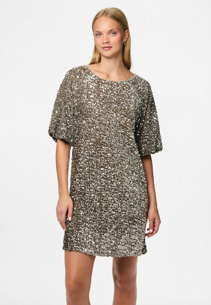 Krátké, třpytivé šaty pokryté stříbrnými a bronzovými flitry. Mají volný střih, krátké rukávy a kulatý výstřih.