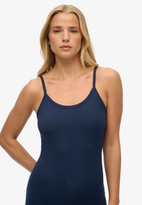 Granatowy top na ramiączkach z cienkimi paskami i okrągłym dekoltem, wykonany z gładkiego, elastycznego materiału; dopasowany krój z estetycznym wykończeniem.