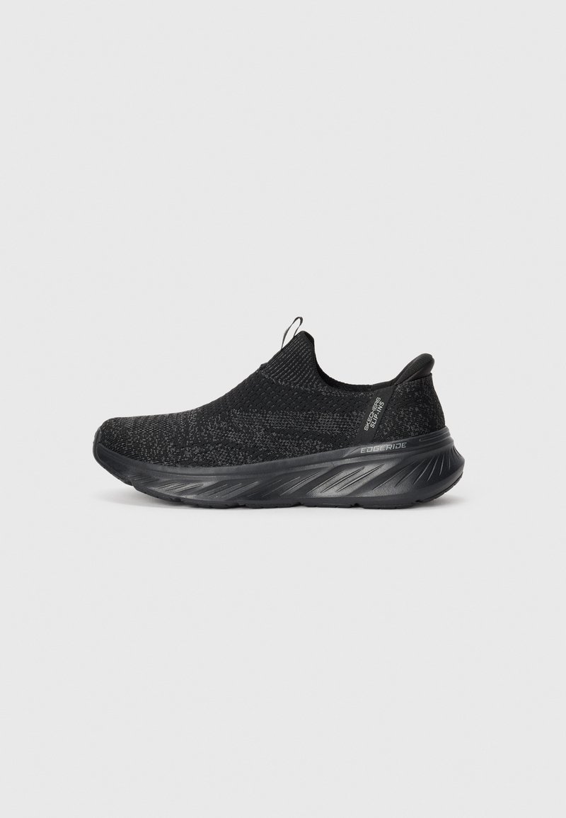 Black slip-on sneaker with a knitted upper and textured finish. Features a cushioned sole with a curved shape and pull tab at the back.