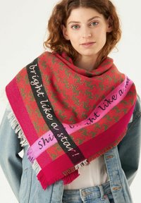 Grote rode en roze gestreepte sjaal met een houndstooth ontwerp, voorzien van geborduurde tekst op zwarte en roze strepen, afgewerkt met franjes.