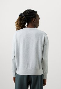 Svetlo šedý sveter z jemného materiálu, s voľným strihom, raglánovými rukávmi a rebrovanými lemami, s výstrihom do kruhu.