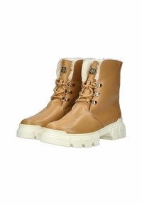 Botas de imitación cuero color tan con forro de piel sintética, que cuentan con ojales metálicos, cordones y una suela blanca gruesa. Textura suave y diseño hasta la pantorrilla.