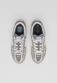 Nike sneakers with a mesh upper in light gray and purple accents, featuring white laces, a cushioned midsole, and a textured outsole.