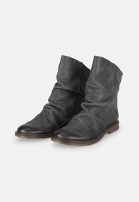 Botas de tobillo de ante negro con un diseño arrugado, punteras redondeadas y un tacón bajo y apilado. Superficie texturizada con un detalle mínimo.