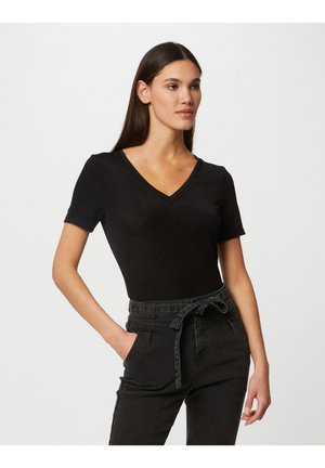 Haut noir à manches courtes et col en V, fabriqué à partir d'un tissu texturé, associé à un pantalon gris foncé taille haute avec une ceinture nouée et des poches latérales.