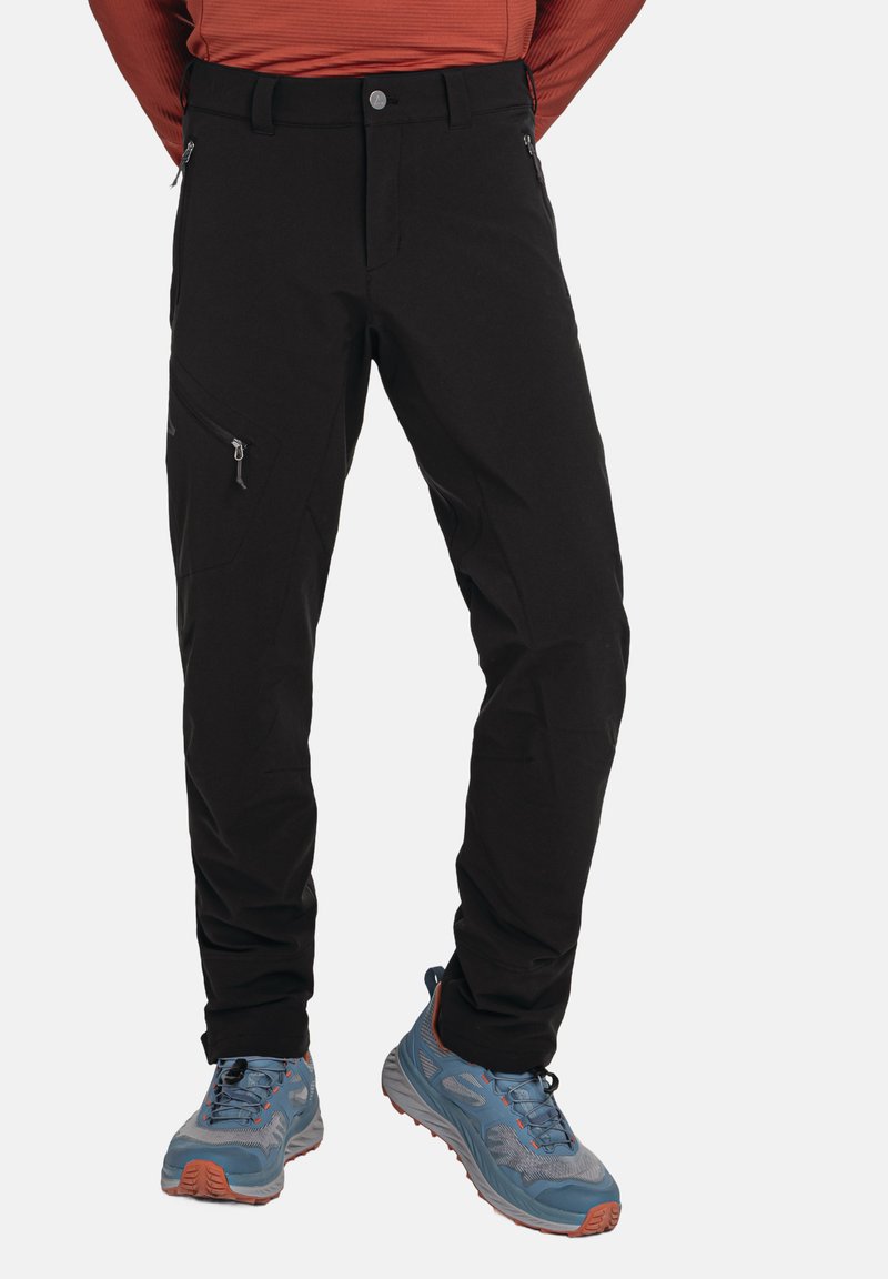 Schwarze Sporthose mit einem figurbetonten Design, ausgestattet mit seitlichen Reißverschlusstaschen und einer glatten Textur, kombiniert mit blauen und grauen Wanderschuhen.