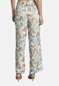 Pantalons fluides et légers avec un motif floral multicolore dans des tons de bleu, marron et blanc. Dotés d'une taille élastique et d'une coupe large.