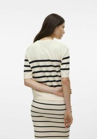 Stripet strikket topp med korte ermer i krem og svart. Har horisontale striper, rund hals og ribbestruktur.
