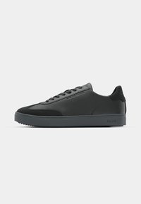 Black sneaker with a smooth leather upper and suede accents. Featuring a rounded toe, flat laces, and a textured rubber sole.