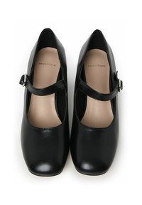 Zapatos Mary Jane de cuero negro con punta redondeada, tacón plano y una correa con hebilla en la parte superior. El interior presenta un forro suave en color beige.