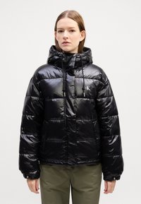 Svart puff jakke med glansfull overflate, hette og snøring, med horisontale quiltede seksjoner og en liten logo på brystet.