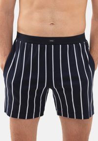 Marineblauwe boxershort met witte verticale strepen, elastische tailleband met logo, twee zijzakken, zachte stof met een gladde textuur.