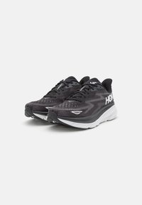 Scarpe sportive nere realizzate in mesh traspirante con un motivo testurizzato, dotate di un logo bianco e di una suola ammortizzata per il massimo comfort.