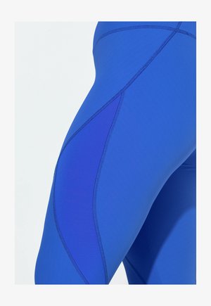 Niebieskie legginsy wykonane z rozciągliwej, teksturowanej tkaniny o kontrastujących odcieniach i szwach. Projekt wyróżnia się unikalnym panelem po bokach.