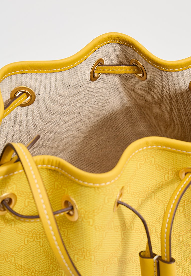 Gelbe Buckettasche mit strukturiertem Äußeren, glatten Kanten und braunen Lederelementen. Das Innenfutter hat eine beige Auskleidung und dekorative Nähte.