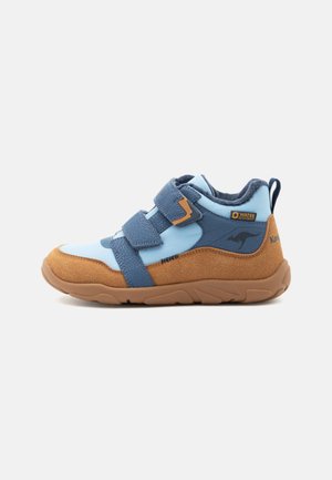 Basket enfant montante avec panneaux bleu et beige, deux bandes bleues à scratch, logo kangourou et étiquette imperméable sur le côté.