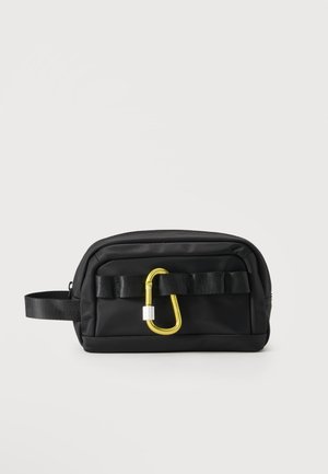 Zwarte rechthoekige etui met rits, zijhandvat en gouden karabijnhaak vastgeklikt aan een zwarte webbing lus aan de voorkant.