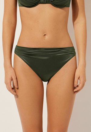 Bas de bikini vert en matériau lisse et extensible. Présente une taille large avec des détails froncés. Coupe à taille mi-haute et ajustée.