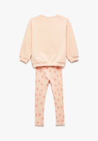 Jasnoróżowy długi rękaw bluza zestawiona z prążkowanymi legginsami z wzorem małych, ciemnoróżowych kwiatów, wyeksponowana na białym tle.