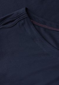 T-shirt en coton bleu marine avec un col rond, texture lisse et coutures contrastantes en rouge.